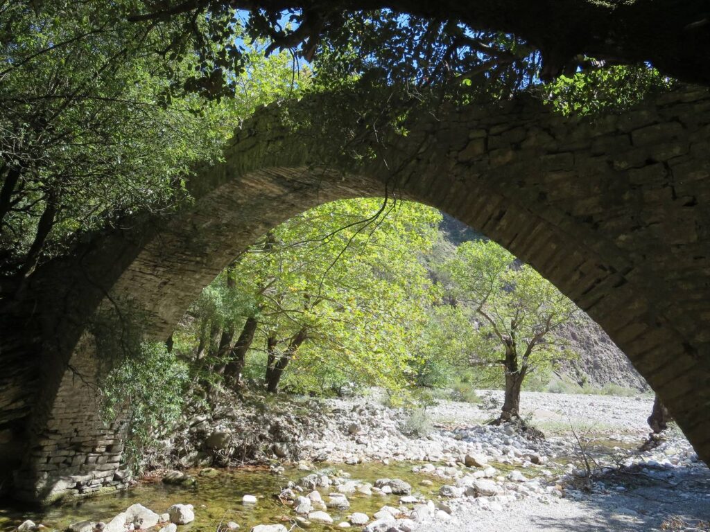 Route from Epiniana: traditional stone bridge over Agrafiotis tributary, with small pools of water and trees
