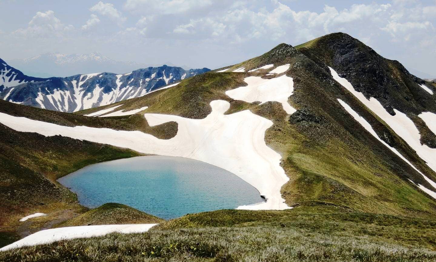 Deep turquoise dragon lake below Grammos snowy peaks