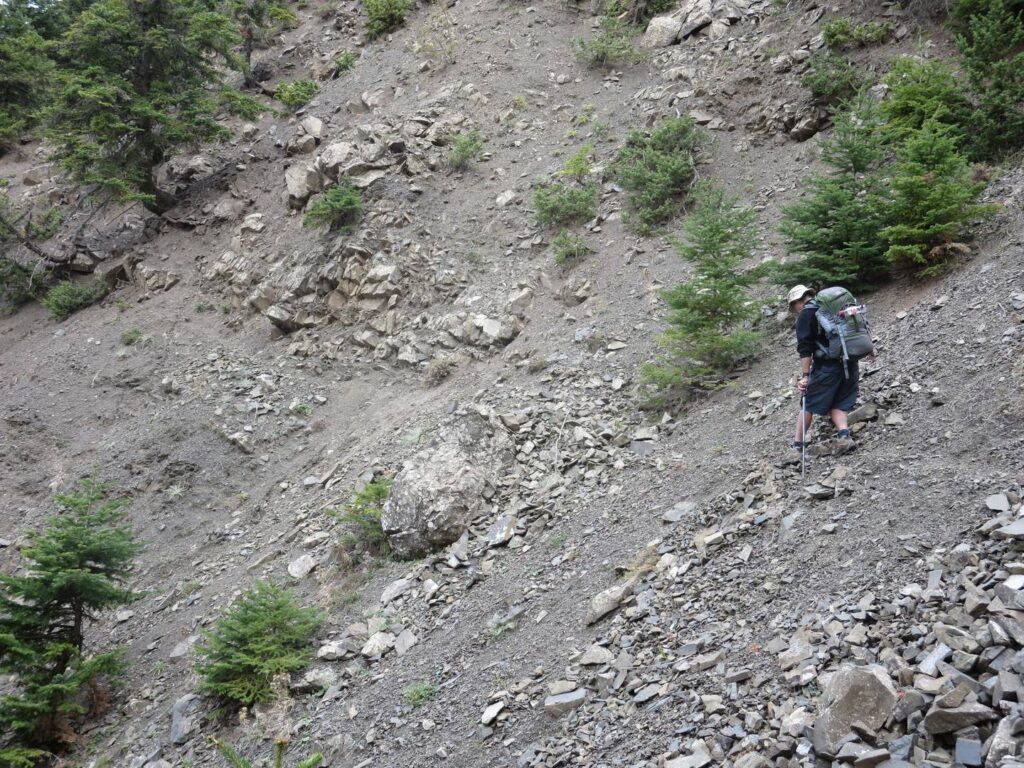 E4 below Vardhousia: faint path over scree with hiker.