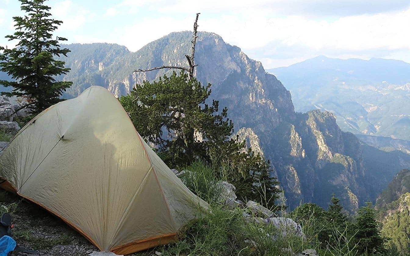 Tent on the edge of a precipice looking out to the Timfi crags beyond. No flat options.